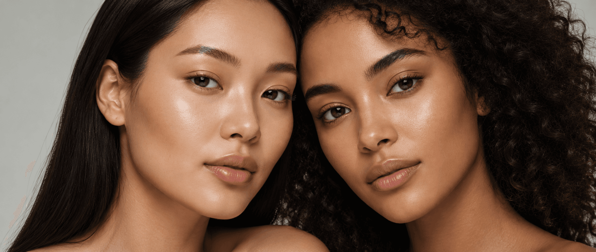 Two women photographed cheek to cheek with clear, even skin